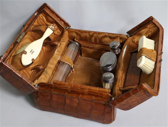 An early 20th century Harrods crocodile skin toilet case containing four silver mounted toilet jars, Wolfsky & Co, London, 1905,